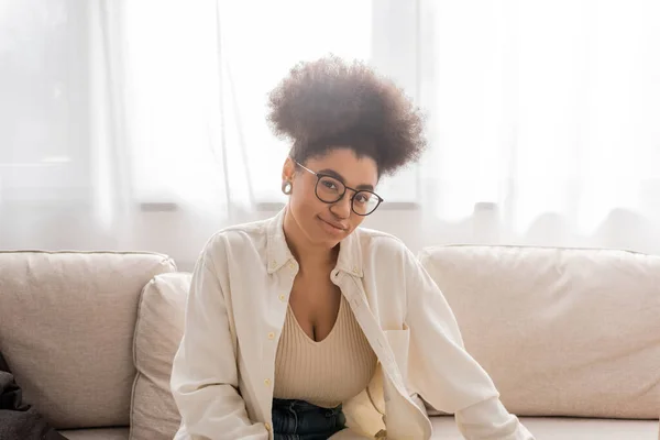 Despreocupado mujer afroamericana en gafas mirando a la cámara en casa - foto de stock