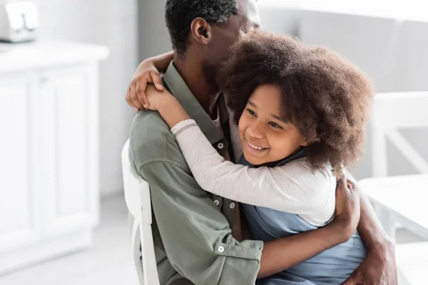 Happy african american child with curly hair hugging middle aged grandfather at home — Stock Photo