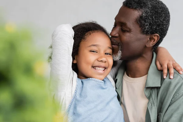 Africano americano abuelo besos cabeza de feliz nieta en casa - foto de stock