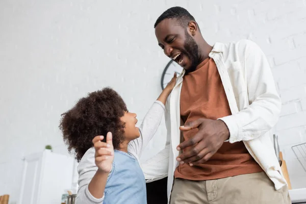 Low-Winkelansicht des lockigen afrikanisch-amerikanischen Kindes streckt die Hand in Richtung glücklicher Vater, bevor sie sich umarmen — Stockfoto