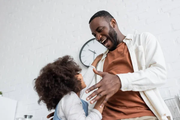 Niedrigwinkel-Ansicht von afrikanisch-amerikanischen Mann streckt die Hand in Richtung lockige Tochter, bevor sie einander umarmen — Stockfoto