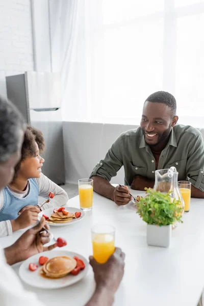 Feliz afroamericano chica mirando alegre padre mientras teniendo familia desayuno - foto de stock