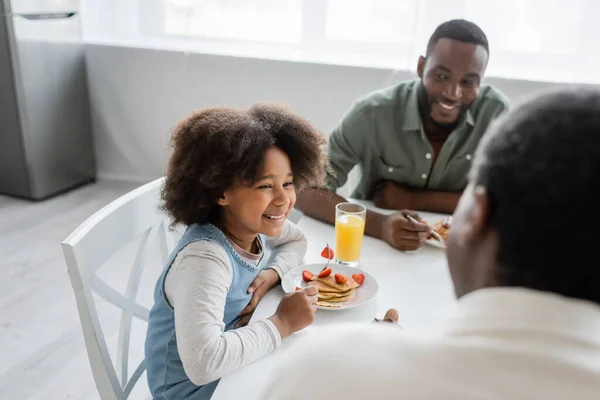 Alegre africano americano niño mirando abuelo cerca feliz padre mientras teniendo familia desayuno - foto de stock
