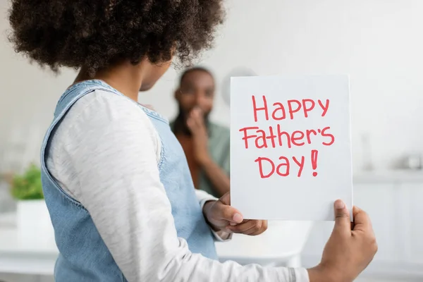 Curly african american girl holding greeting card with happy fathers day lettering — Stock Photo