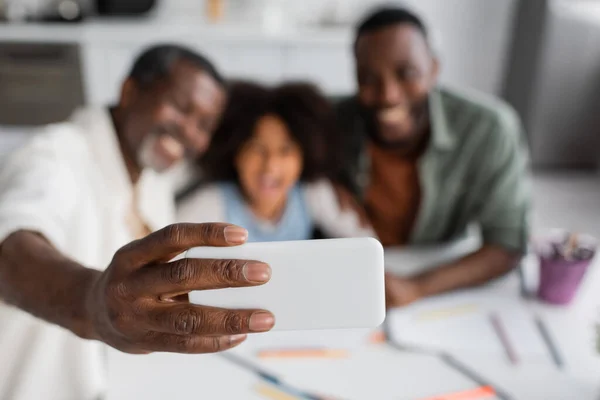 Blurred african american grandfather taking selfie with granddaughter and son at home — Stock Photo