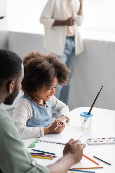 Positive african american kid painting with father at home — Stock Photo