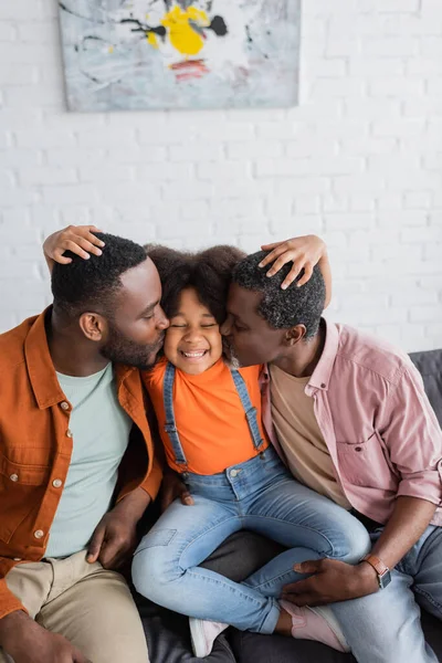 Afroamericano nonno e padre baciare allegra ragazza sul divano a casa — Foto stock