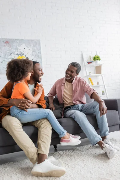 Fröhliche afrikanisch-amerikanische Vater und Kind im Gespräch mit Großeltern auf der Couch zu Hause — Stockfoto