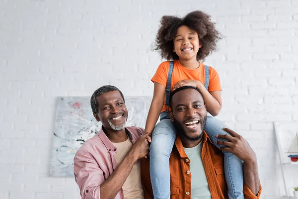 Overjoyed african american kid having fun with father and granddad at home — Stock Photo