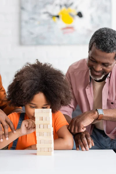 Африканский американский ребенок играет деревянные блоки игры с папой и дедушкой дома — стоковое фото