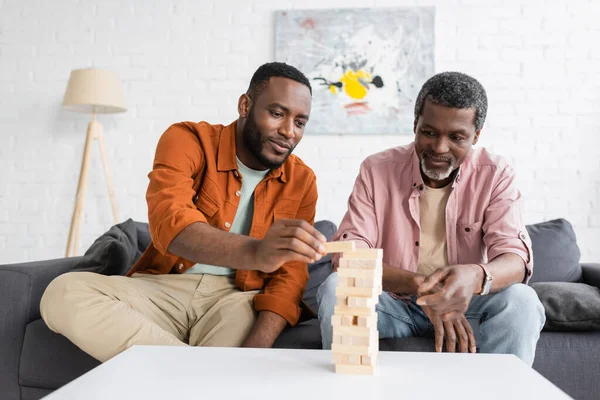 African american man playing wood blocks game with father at home — Stock Photo
