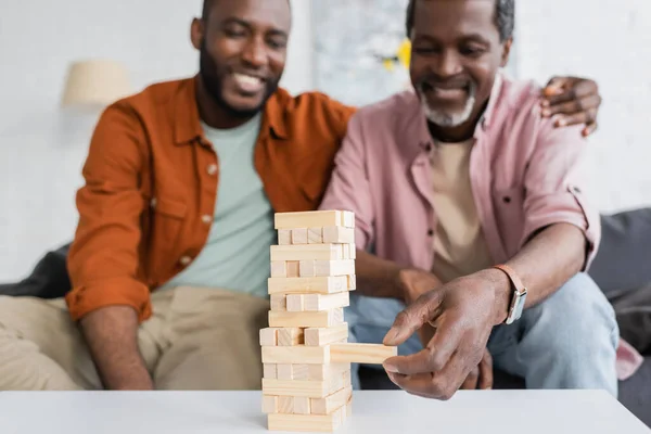 Blurred african american man playing wood blocks game with son in living room — Stock Photo