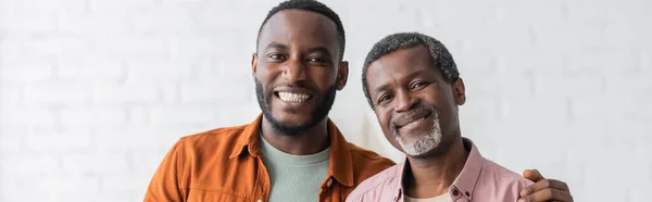 Glückliche afrikanisch-amerikanische Mann umarmt mittleren Alters Papa zu Hause, Banner — Stockfoto