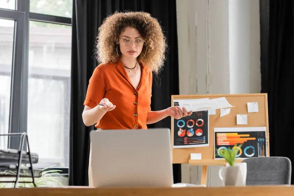 Curly businesswoman in glasses doing online presentation during video call — Stock Photo