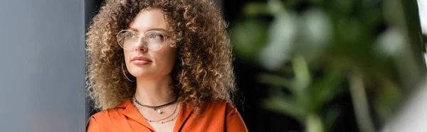 Pensive businesswoman with curly hair looking away while thinking in modern office, banner — Stock Photo