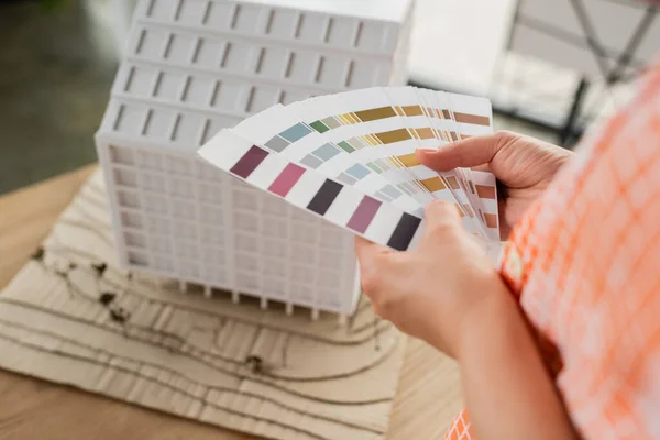 Vista parziale del progettista che tiene tavolozza dei colori vicino al modello di casa in ufficio — Foto stock