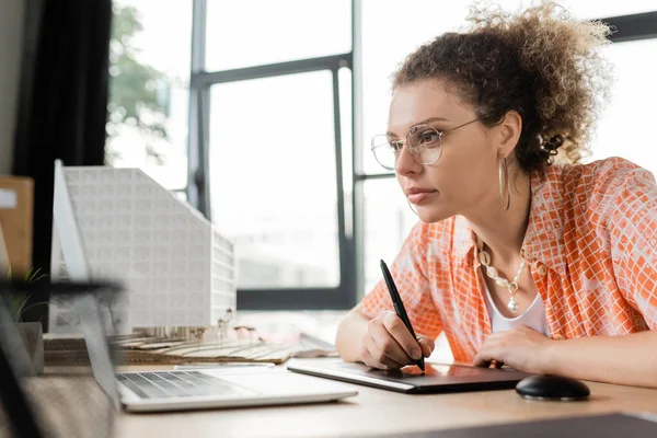 Focused architectural designer using graphic tablet and looking at laptop while working in office — Stock Photo