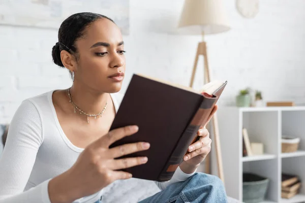 Estudante afro-americano focado lendo livro em casa — Fotografia de Stock