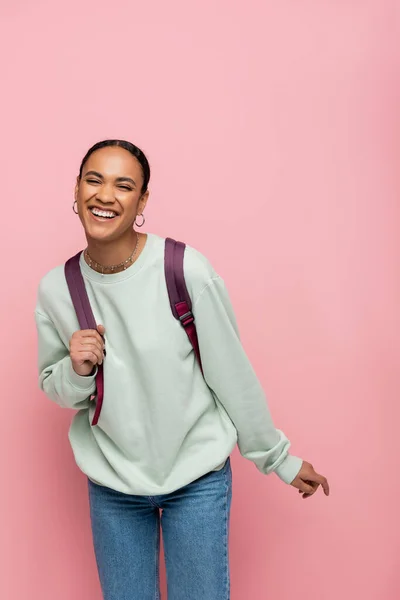 Sonriente joven afroamericano estudiante de pie aislado en rosa - foto de stock