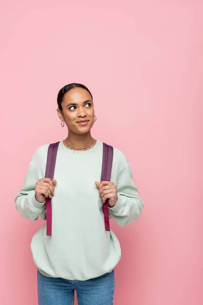 Hübsche afrikanisch-amerikanische Studentin mit Rucksack und Blick weg isoliert auf rosa — Stockfoto