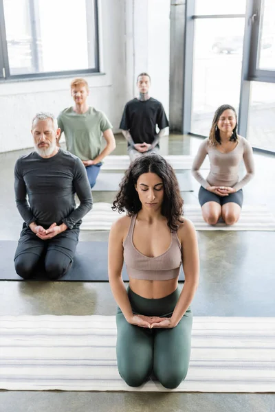 Middle eastern woman meditating in Thunderbolt pose on mat in yoga class — Stock Photo