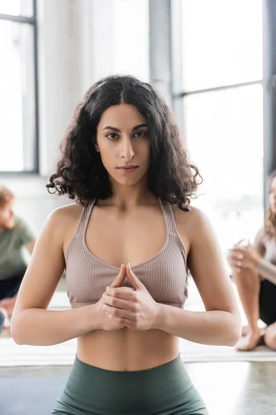 Mulher do Oriente Médio meditando e olhando para a câmera na aula de ioga — Fotografia de Stock