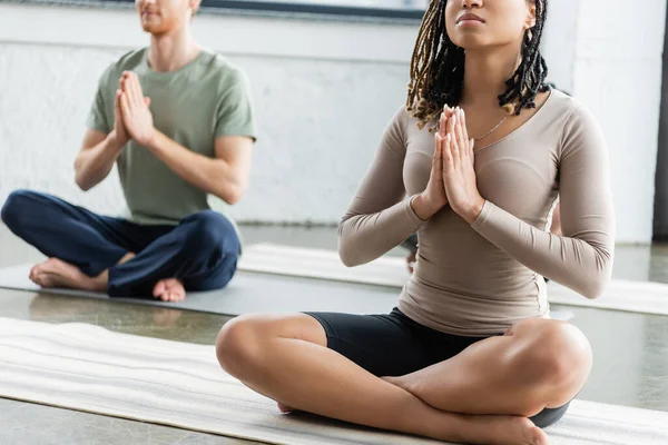 Vista recortada de una mujer afroamericana practicando anjali mudra en clase de yoga - foto de stock