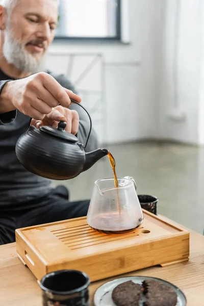 Verschwommene reife Mann gießt Tee aus Kanne in Yoga-Klasse — Stockfoto