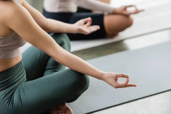 Vista recortada de mujer en ropa deportiva practicando gyan mudra en estudio de yoga - foto de stock