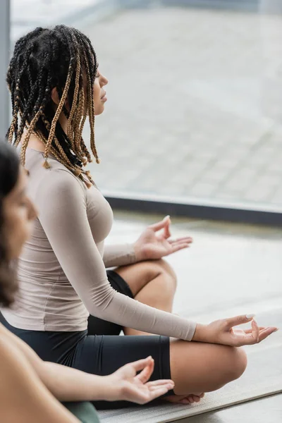 Vista lateral da mulher americana africana fazendo mudra gyan no estúdio de ioga — Fotografia de Stock