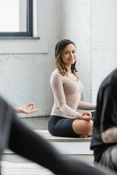 Carefree african american woman looking at camera while doing gyan mudra in yoga class — Stock Photo