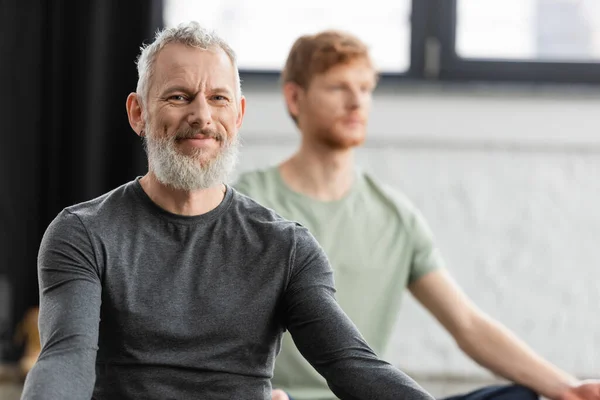 Бородатий чоловік середнього віку посміхається на камеру в студії йоги — стокове фото