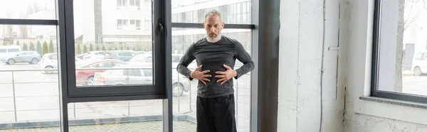 Reifer Mann in Sportbekleidung, der den Bauch berührt, während er Yoga im Unterricht praktiziert, Banner — Stockfoto