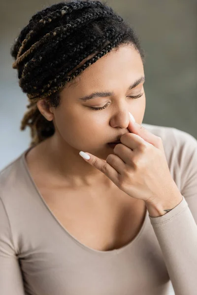 Joven mujer afroamericana practicando respiración nasal y meditación en estudio de yoga - foto de stock