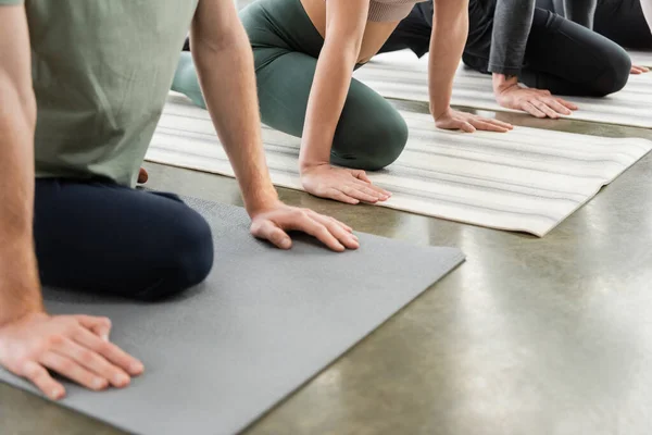Cropped view of people doing Half Pigeon asana on mats in yoga class — Photo de stock