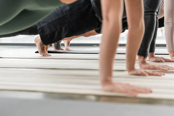 Обрізаний вид групи людей, що стоять на дошці на килимках йоги в студії — стокове фото