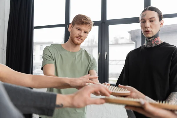 Men looking at blurred group holding sadhu board in yoga class — Stock Photo