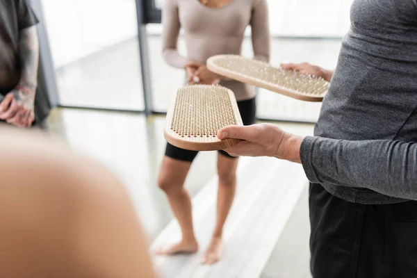Cropped view of man holding sadhu board near blurred group in yoga class — Stock Photo
