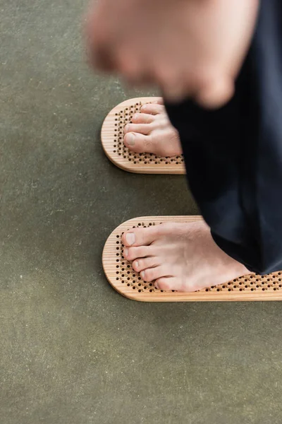 Top view of cropped man stepping with bare feet on sadhu board in yoga studio — Stock Photo