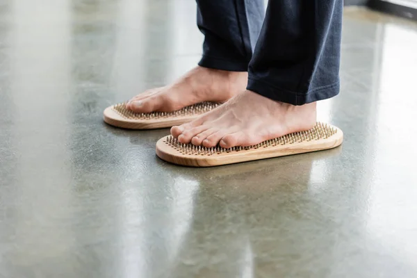 Vista cortada do homem de pé com os pés descalços na placa sadhu no estúdio de ioga — Fotografia de Stock