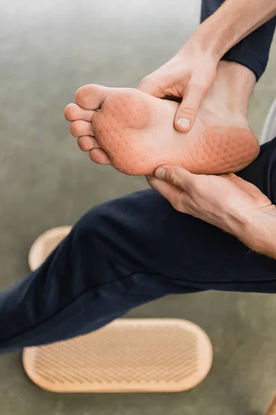 Cropped view of man showing bare feet after nail standing practice in yoga studio — Stock Photo
