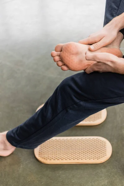 Vista parcial del hombre mostrando los pies desnudos después de la práctica de pie clavo en el estudio de yoga - foto de stock