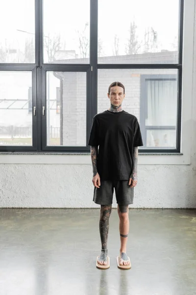 Босоніж чоловік з татуйованими ногами, що стоять на дошці для нігтів Садху в студії йоги — стокове фото