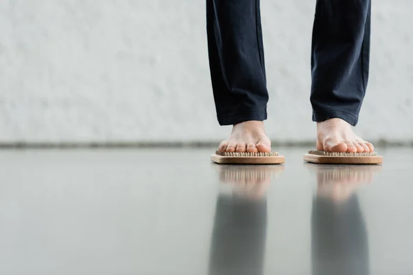 Обрізаний вид людини в штанях, що стоять на дошці для нігтів Садху в студії йоги — стокове фото