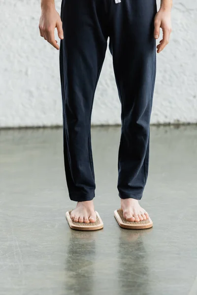 Vista parcial del hombre descalzo en pantalones de pie sobre tabla de sadhu en estudio de yoga - foto de stock