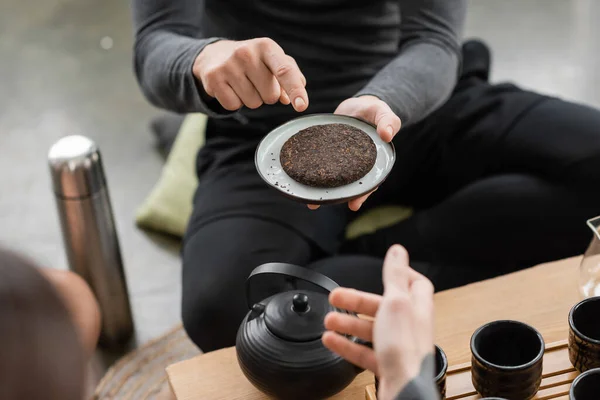 Cropped view of man pointing with finger at compressed puer tea in yoga studio — Stock Photo