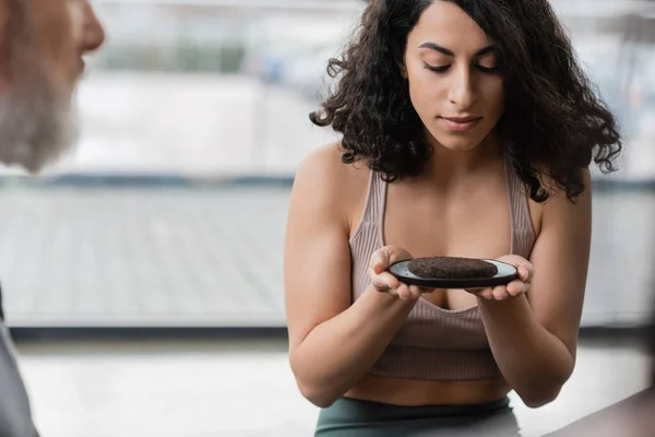 Женщина с Ближнего Востока смотрит на тарелку со сжатым чайником в студии йоги — стоковое фото