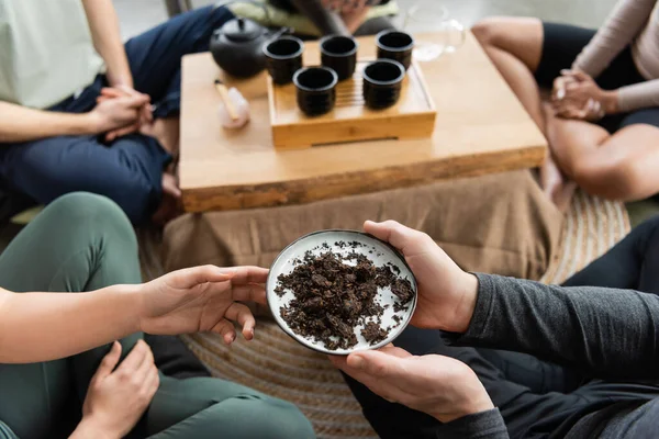 Top view of african american man passing plate with fermented puer tea in yoga studio — Stock Photo