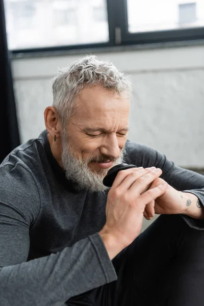 Homem feliz de meia idade com tatuagens e olhos fechados desfrutando aroma de chá puer — Fotografia de Stock