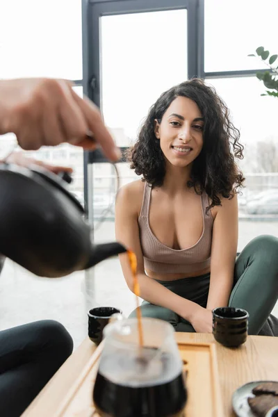 Happy middle eastern woman looking at man pouring puer tea into glass jug — Stock Photo